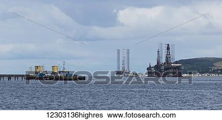 Stock Photograph - Boats at the end of a pier in a harbour; Invergordon, Scotland. Fotosearch