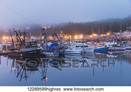 Stock Photograph - Boats in Ketchikan Harbor reflecting on the calm ocean waters on a foggy night, Ketchikan, Southeast Alaska. Fotosearch