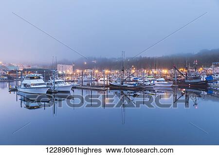 Stock Photograph - Boats in Ketchikan Harbor reflecting on the calm ocean waters on a foggy night, Ketchikan, Southeast Alaska. Fotosearch