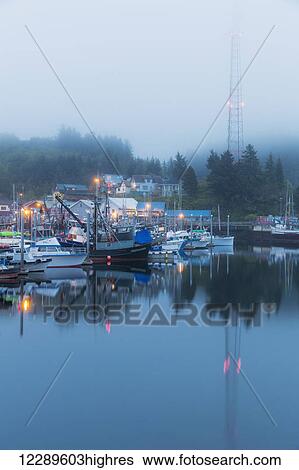 Stock Photograph - Boats in Ketchikan Harbor reflecting on the calm ocean waters on a foggy night, Ketchikan, Southeast Alaska. Fotosearch