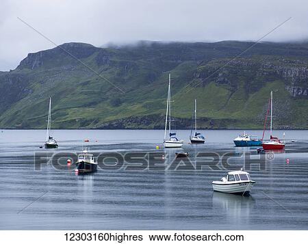 Stock Photograph - Boats moored in the tranquil water of a harbour, Skye Island; Portree, Scotland. Fotosearch