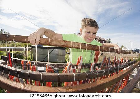 Stock Photograph - Boy looking over drying rack of salmon at fish camp in Bristol Bay, Southwest Alaska, Summer. Fotosearch
