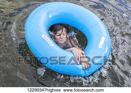 Stock Photograph - Boy playing with blue inflatable ring on Balsam Lake; Ontario, Canada. Fotosearch