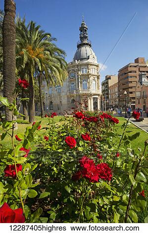 Stock Photograph - Carthagenian Town Hall on the Murcia Coast with blossoming flowers in the foreground; Cartagena, Spain. Fotosearch