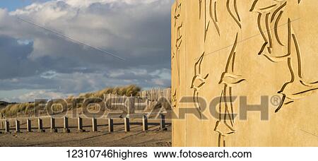 Stock Photograph - Carvings of birds in a wall with a view of a wooden fence and tall grasses; South Shields, Tyne and Wear, England. Fotosearch