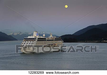 Stock Photo - Celebrity cruise ship Oceania leaves Juneau harbor as the moon rises over the Inside Passage, Southeast Alaska. Fotosearch