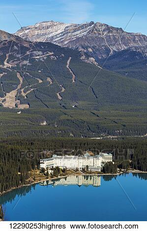 Chateau Lake Louise reflected in the tranquil intense blue mountain lake with ski hill runs in the background and blue sky; Lake Louise, Alberta, Canada View Large Photo Image Stock Photograph - Chateau Lake Louise reflected in the tranquil intense blue mountain lake with ski hill runs in the background and blue sky; Lake Louise, Alberta, Canada. Fotosearch