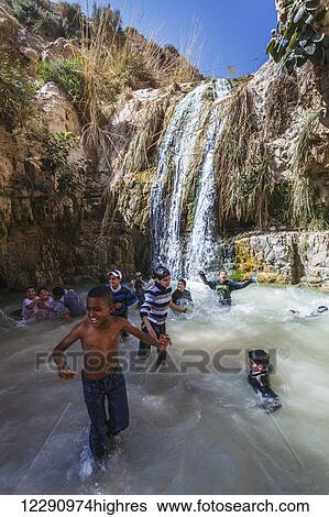 Stock Photograph - Children play in a waterfall and pool; Ein Gedi, Israel. Fotosearch