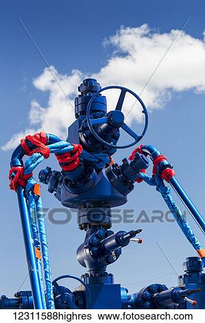 Stock Photograph - Close up of a clean newly painted oil well head with blue sky and clouds; Calgary, Alberta, Canada. Fotosearch
