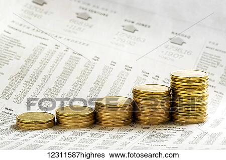 Stock Photograph - Close up of a row of stacked coins (loonie) on a financial paper background, getting higher on each stack; Calgary, Alberta, Canada. Fotosearch