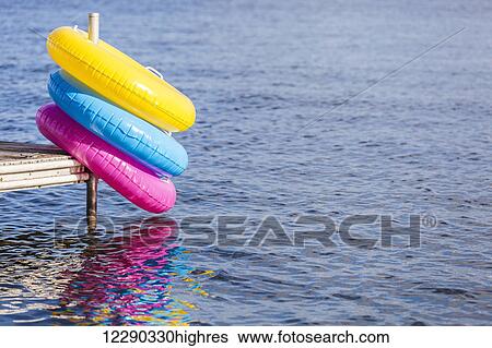 Colorful inflatable rings hanging off end of dock by Balsam Lake; Ontario, Canada View Large Photo Image Stock Photograph - Colorful inflatable rings hanging off end of dock by Balsam Lake; Ontario, Canada. Fotosearch
