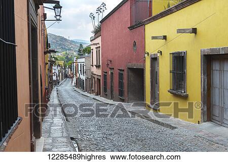 Stock Photograph - Colourful buildings lining a cobblestone street; San Miguel de Allende, Guanajuato, Mexico. Fotosearch