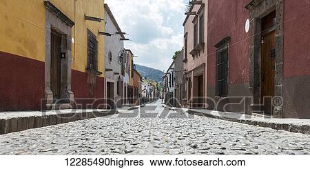 Stock Photograph - Colourful buildings lining a cobblestone street; San Miguel de Allende, Guanajuato, Mexico. Fotosearch