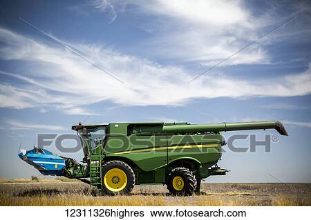 Stock Photograph - Combine sits under blue skies during wheat harvest in Northeast Colorado; Paoli, Colorado, United States of America. Fotosearch