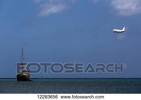Commercial passenger airplane on approach to Aruba's international airport, flying over blue sea and fishing trawler, Surfside Beach; Aruba View Large Photo Image Stock Photograph - Commercial passenger airplane on approach to Aruba's international airport, flying over blue sea and fishing trawler, Surfside Beach; Aruba. Fotosearch