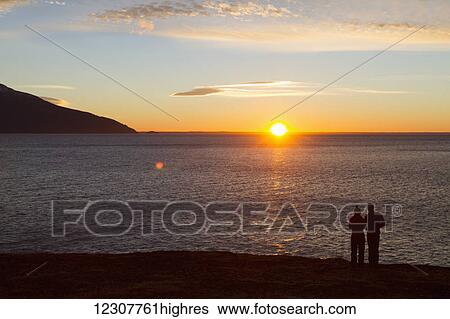 Stock Photograph - Couple viewing sunset over Turnagain Arm, Southcentral Alaska, Winter.. Fotosearch