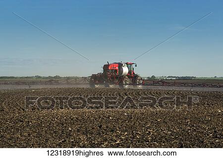 Stock Photograph - Crop sprayer in clean soil field with blue sky and clouds, East of Calgary; Alberta, Canada. Fotosearch