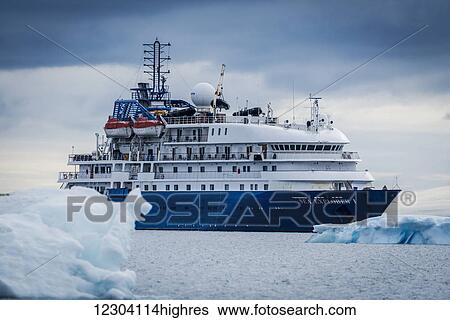 Stock Photograph - Cruise ship at anchor between blue icebergs; Antarctica. Fotosearch