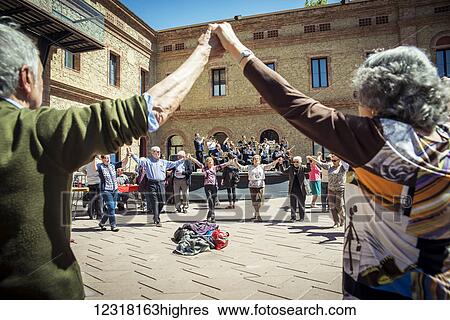 Stock Photograph - Dancing in the town square in 0u Barris district during Saint George's Day festivities, with a band on the stage in the background; Barcelona, Catalonia, Spain. Fotosearch
