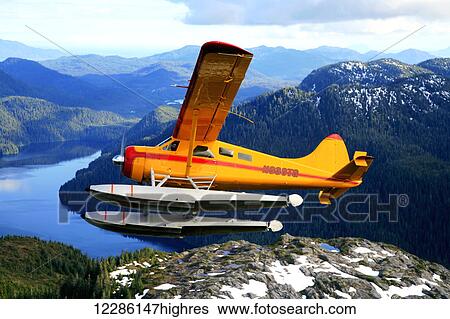 Stock Photograph - DeHavilland Beaver floatplane over the waters of Mirror Lake in the Misty Fiord National Monument Wilderness, Southeast Alaska, Summer. Fotosearch
