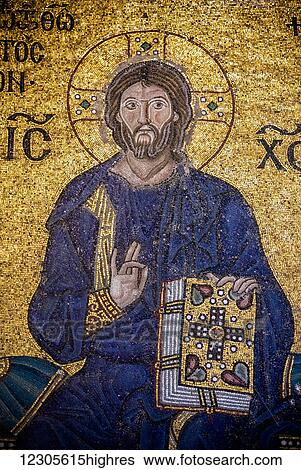 Stock Photograph - Detail of the Empress Zoe mosaic, Christ is clad in the dark blue robe (as is the custom in Byzantine art), is seated against a golden background, giving His blessing with the right hand and holding the Bible in His left hand; Istanbul, Turkey. Fotosearch