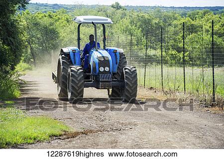 Stock Photograph - Farmer driving blue tractor; Roodeplaat, Gautang, South Africa. Fotosearch