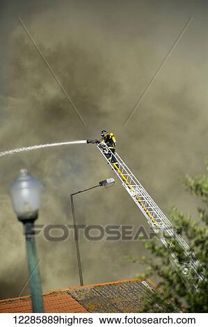 Stock Photograph - Firefighter spraying water on building fire; Lisbon, Portugal. Fotosearch
