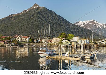 Stock Photograph - Fishing boat moored along the pier in Sitka Harbor and the mountains in the background, Southeast Alaska, USA, Summer. Fotosearch