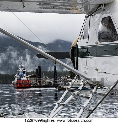 Stock Photograph - Float plane near docked boat; Tofino, Vancouver Island, British Columbia, Canada. Fotosearch