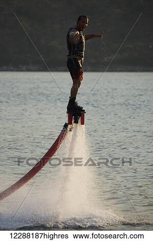 Stock Photograph - Flyboarder with arms out looking towards camera; Torba, Mugla Province, Turkey. Fotosearch