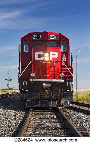 Picture - Front of a red train engine straight on the tracks; Crossfield, Alberta, Canada. Fotosearch