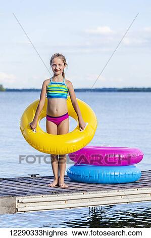 Girl on dock by Balsam Lake holding a yellow inflatable ring; Ontario, Canada View Large Photo Image Stock Photograph - Girl on dock by Balsam Lake holding a yellow inflatable ring; Ontario, Canada. Fotosearch