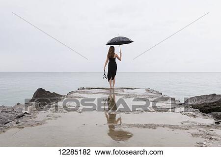 Girl standing at end of pier holding umbrella; Toronto, Ontario, Canada View Large Photo Image Stock Image - Girl standing at end of pier holding umbrella; Toronto, Ontario, Canada. Fotosearch