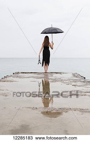 Girl standing at end of pier holding umbrella; Toronto, Ontario, Canada View Large Photo Image Stock Image - Girl standing at end of pier holding umbrella; Toronto, Ontario, Canada. Fotosearch
