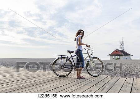 Girl standing by bike on a beach boardwalk; Toronto, Ontario, Canada View Large Photo Image Stock Photo - Girl standing by bike on a beach boardwalk; Toronto, Ontario, Canada. Fotosearch