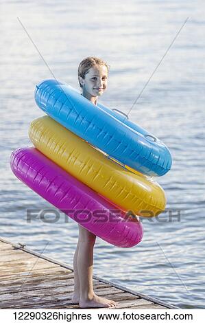 Girl standing on edge of dock by Balsam Lake wearing colorful inflatable rings; Ontario, Canada View Large Photo Image Stock Photograph - Girl standing on edge of dock by Balsam Lake wearing colorful inflatable rings; Ontario, Canada. Fotosearch