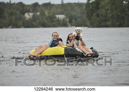 Girls with their pet dog being towed in a rubber raft; Lake of the Woods, Ontario, Canada View Large Photo Image Stock Photograph - Girls with their pet dog being towed in a rubber raft; Lake of the Woods, Ontario, Canada. Fotosearch