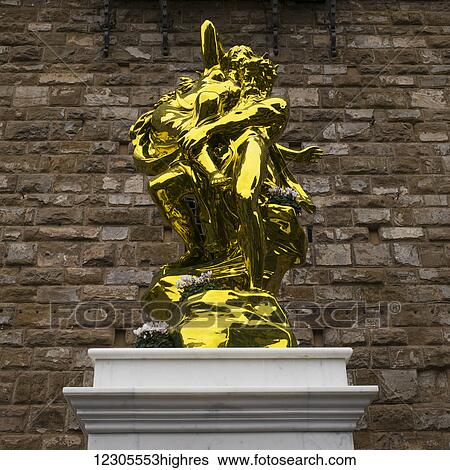 Stock Photograph - Gold statue against a stone wall in Piazza della Signoria; Florence, Italy. Fotosearch