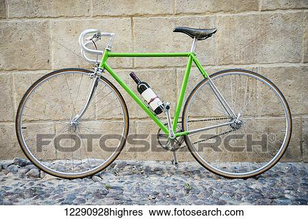 Stock Photograph - Green bicycle with bottle of wine; Alghero, Sardinia, Italy. Fotosearch