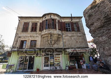 Stock Photograph - Group of men sitting and standing outside a store; Tarsus, Turkey. Fotosearch