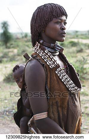 Stock Photograph - Hamar tribe woman carrying baby on her back; Ethiopia. Fotosearch