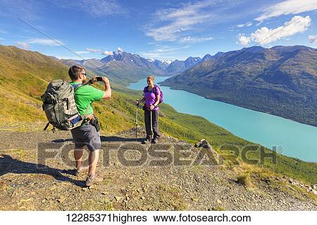 Stock Photograph - Hikers taking pictures along the Twin Peaks Trail, Eklutna Lake, Chugach State Park, Southcentral Alaska, Summer. Fotosearch