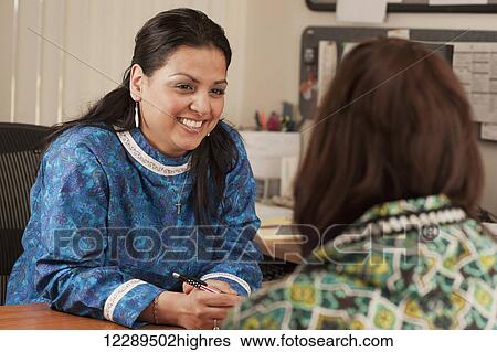 Stock Photograph - Inupiaq professional woman talking with another person in an office, Barrow, North Slope, Arctic Alaska. Fotosearch