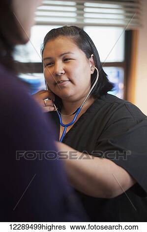 Inupiaq woman nurse checking a patient's heartbeat with a stethascope in the native hospital, Barrow, North Slope, Arctic Alaska View Large Photo Image Stock Photograph - Inupiaq woman nurse checking a patient's heartbeat with a stethascope in the native hospital, Barrow, North Slope, Arctic Alaska. Fotosearch