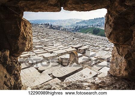Stock Photograph - Jewish graves viewed from a hole in the wall of a walkway that leads down the Mount of Olives; Jerusalem, Israel. Fotosearch