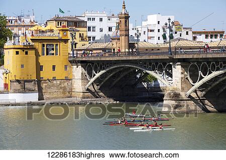 Stock Photograph - Kayakers passing under the Triana Bridge on the Guadalquivir River; Seville, Spain. Fotosearch
