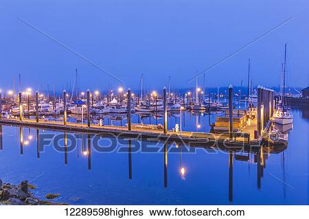 Stock Photograph - Ketchikan Harbor reflecting on the calm ocean waters on a foggy night, Ketchikan, Southeast Alaska, HDR Image. Fotosearch