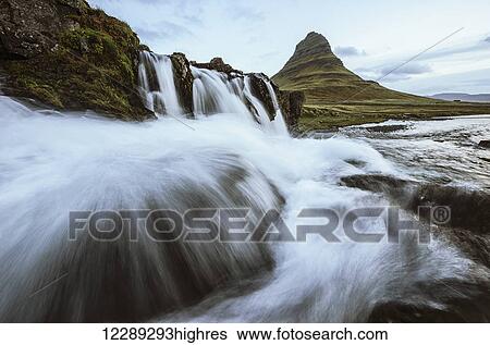 Kirkjufell is seen here as a waterfall flows in front of the camera, Snaefellsness peninsula; Iceland View Large Photo Image Stock Photograph - Kirkjufell is seen here as a waterfall flows in front of the camera, Snaefellsness peninsula; Iceland. Fotosearch