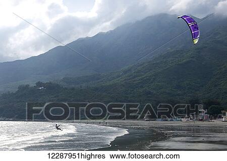 Stock Photograph - Kite surfer and purple kite near beach; New Territories, Hong Kong, China. Fotosearch