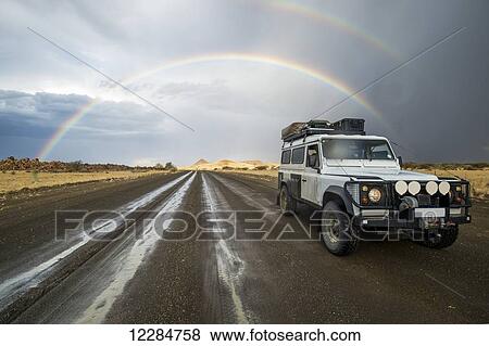 Land Rover driving down wet road with rainbow arching in the sky behind it; Keetmanshoop, Namibia View Large Photo Image Stock Photo - Land Rover driving down wet road with rainbow arching in the sky behind it; Keetmanshoop, Namibia. Fotosearch